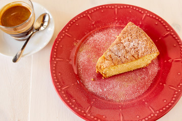 A piece of delicious carrot pie on a red shiny plate. Part of a homemade cupcake on a plate with black coffee. Homemade pie on a ceramic plate on a white wooden table.