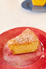 A piece of delicious carrot pie on a red shiny plate. Part of a homemade cupcake on a plate. Homemade pie on a ceramic plate on a white wooden table.