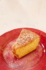 A piece of delicious carrot pie on a red shiny plate. Part of a homemade cupcake on a plate. Homemade pie on a ceramic plate on a white wooden table.