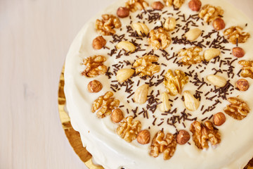 A large delicious pie with walnuts. Homemade pie with white topping and chocolate chips on a white wooden table.