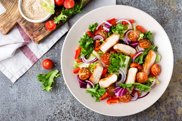 Healthy vegetable salad with grilled chicken breast, fresh lettuce, cherry tomatoes, red onion and pepper