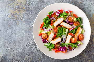 Healthy vegetable salad with grilled chicken breast, fresh lettuce, cherry tomatoes, red onion and pepper