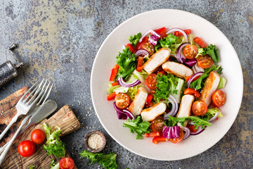 Healthy vegetable salad with grilled chicken breast, fresh lettuce, cherry tomatoes, red onion and pepper