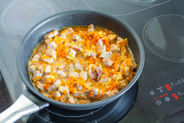 Meat with vegetables is stewed in a frying pan