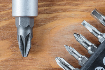 Set of heads (bits) and screwdriver on a wooden table (Flat lay. Corner arrangement)