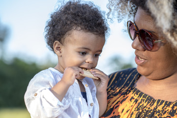 Mother and daughter, african american and mixed race, playing together, daughter is eating a...