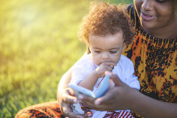 Mother showing her baby daughter some funny and entertaining apps on her cell phone