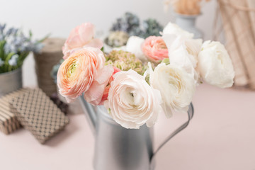 persian buttercup. Bunch colorful ranunculus flowers light background. Metal vase on pink vintage wooden table.