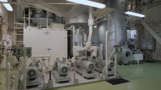 Auxiliary steam boiler with hot well and pumps in engine room of ship