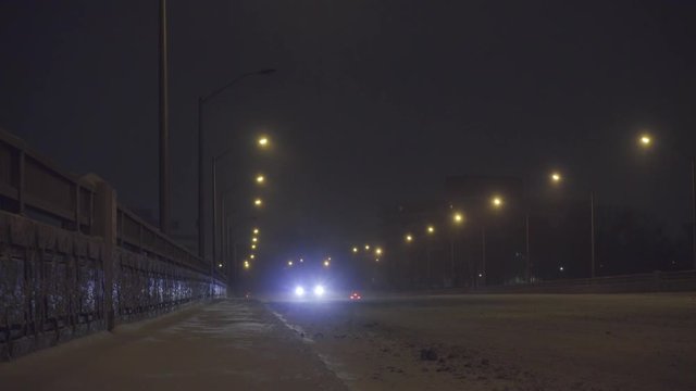 Cars driving on a bridge in the winter storm at night