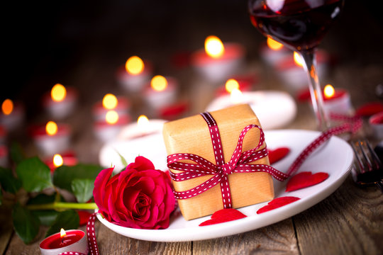 Romantic candle light dinner on Valentines Day with gift box, rose flower and and red wine
