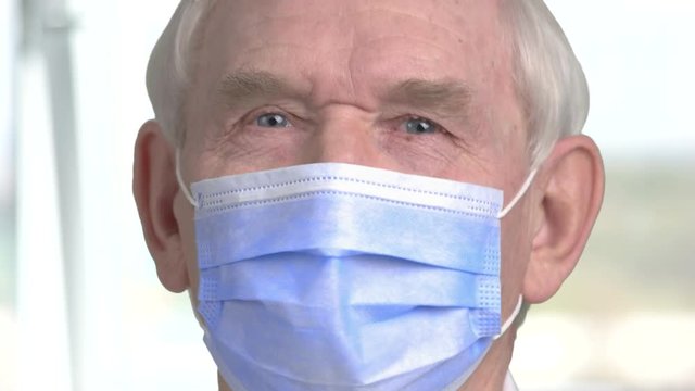 Close up doctor face with mask. Senior old dantist face with protective mask, blurred background.