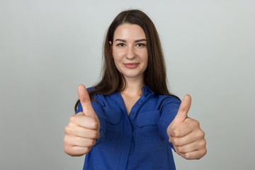 Thumb up. Happy young woman isolated on gray background.