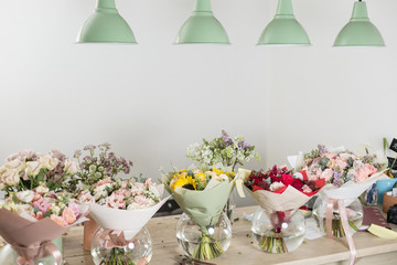 Bouquets on table, florist business. Different varieties fresh spring flowers. Delivery service. Flower shop concept.
