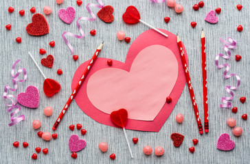 Cute red and white handmade Valentine's day card with red pencils, red and pink candies, sparkle hearts and curled ribbons on grey textured background