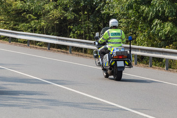 Obraz premium Policeman riding on a motorbike, rear view