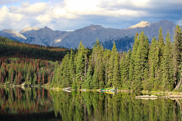 Canoes on a lake shore with mountains in the background