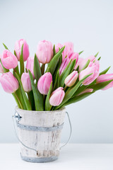 Spring easter tulips in bucket on white vintage background.