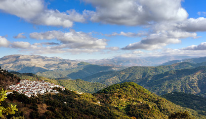 Fototapeta na wymiar Green landscape with cloudy sky and small town among mountains in Andalusia, Spain