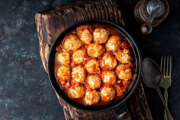 Homemade meatballs stewed in tomato sauce in cast iron pan