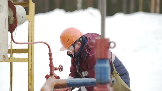 Oil Worker and Pump Jack, Worker in action at pump jack oil well
