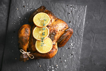 Delicious whole roasted chicken with orange served on slate plate