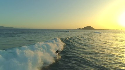 AERIAL Pro male surfer on surfboard riding the waves and falling in the early morning time. Sunrise exercise for a fit sportsman enjoying his action packed vacation. Surfers paradise in Canary Islands