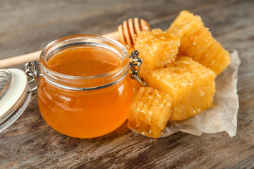 Jar with sweet honey and combs on wooden table