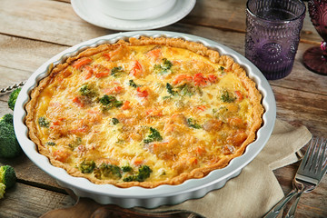 Baking dish with tasty broccoli quiche on table
