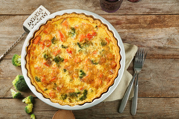 Baking dish with tasty broccoli quiche on table