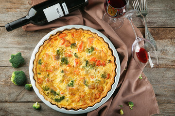Tasty broccoli quiche served with wine on table