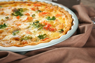 Baking dish with tasty broccoli quiche on table, closeup