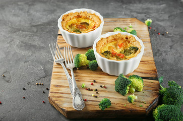 Ramekins with tasty broccoli quiche on wooden board