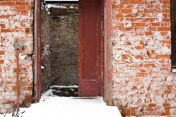 Abandoned brick building with a wooden open door in winter