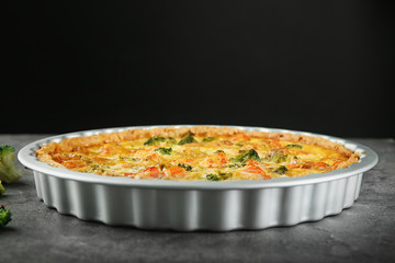 Baking dish with tasty broccoli quiche on table