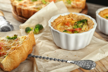 Ramekin with tasty broccoli quiche on table, closeup