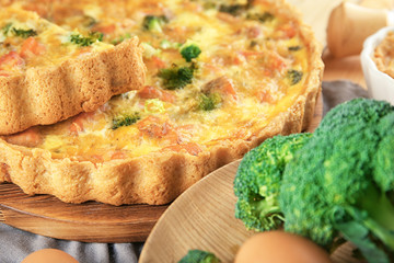 Tasty broccoli quiche on wooden board, closeup