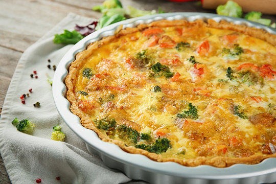 Baking dish with tasty broccoli quiche on table, closeup