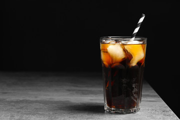 Glass of refreshing cola with ice on table against black background - obrazy, fototapety, plakaty