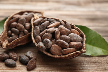 Halves of ripe cocoa pod with beans on wooden background