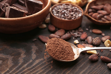 Spoon with cocoa powder on wooden table