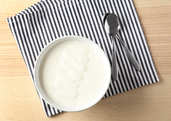 Tasty yogurt in dish on wooden table
