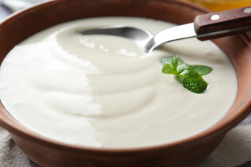 Tasty yogurt in dish with spoon, closeup