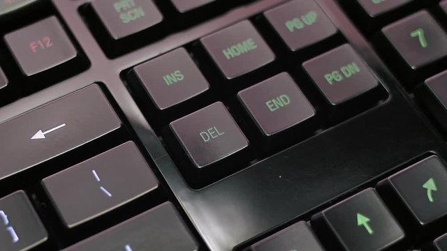 Man pressing delete key on modern illuminated computer keyboard.