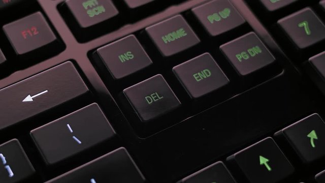 Man pressing delete key on modern illuminated computer keyboard.