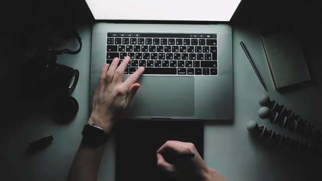 Man photographer is working laptop computer and graphic tablet at dark. Designer flat lay top view