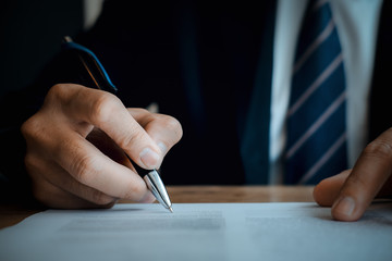 Close up business man reaching out sheet with contract agreement proposing to sign.Full and accurate details, individual who owns the business sign personally,director of the company, solicitor.