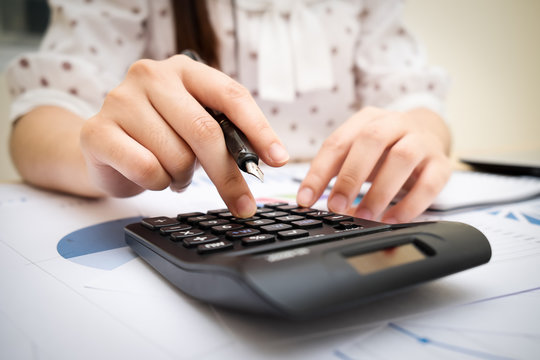 Close up asian woman using a calculator to calculate the numbers.Business finances and accounting concept