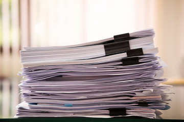 Close up paper stack on the desk related to business functions.Stack of business document files,report paper of accounting and financial with morning light,soft focus