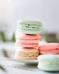 Colorful French or Italian macarons stack on white plate put on wood table with copy space for background. Dessert for served with afternoon tea or coffee break. Beautiful meal background with blank.